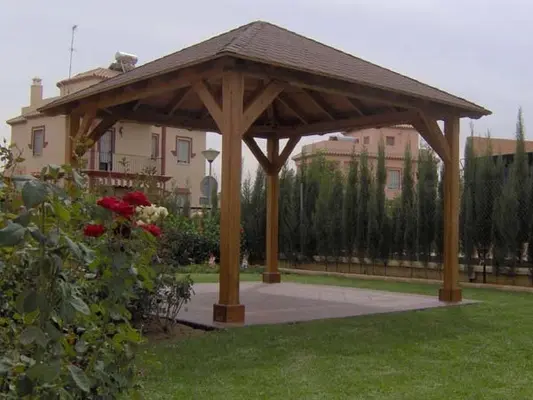 Cenador de madera a cuatro aguas en jardín con césped