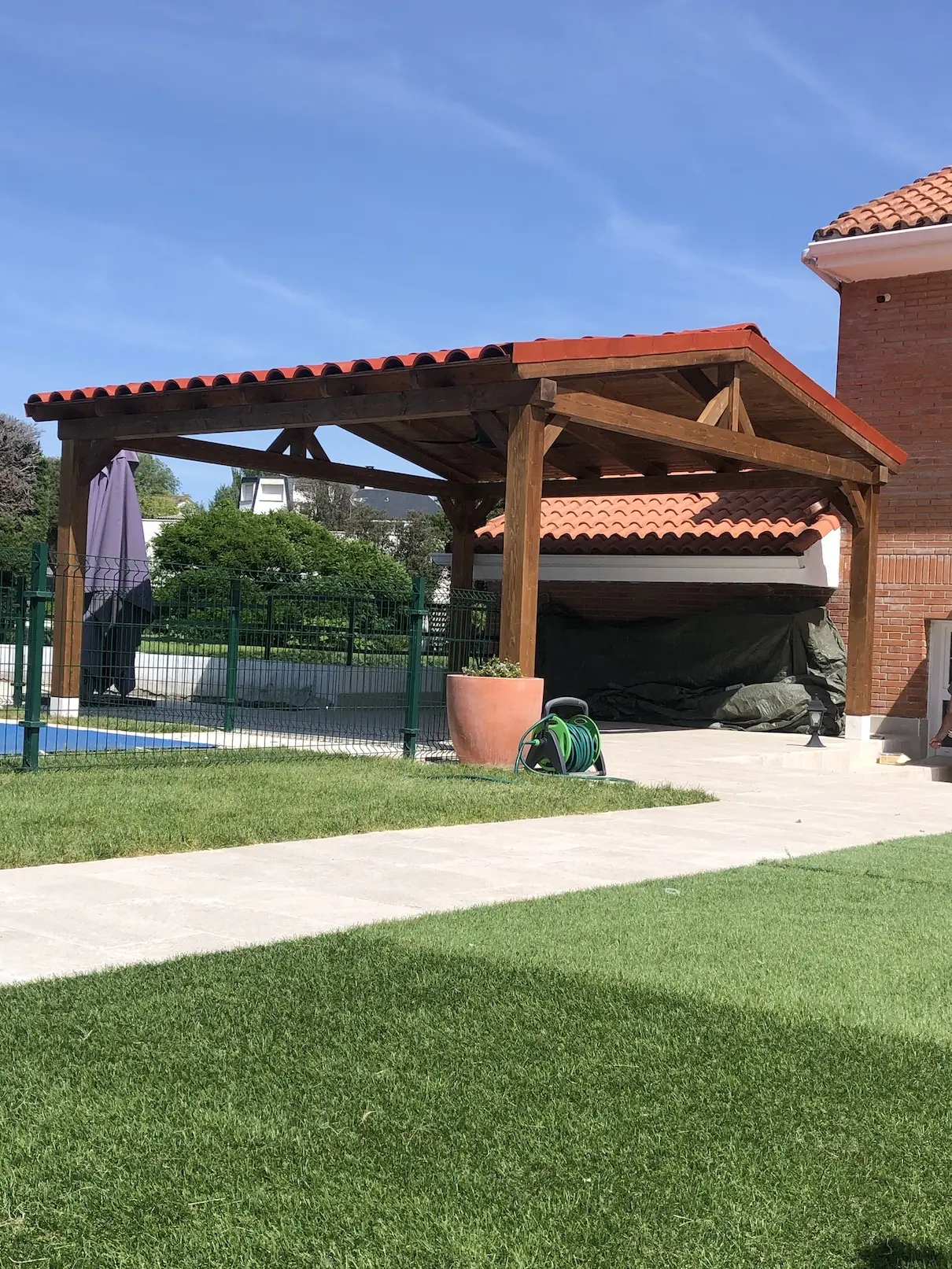Cenador de madera a dos aguas en jardín con cubierta de teja