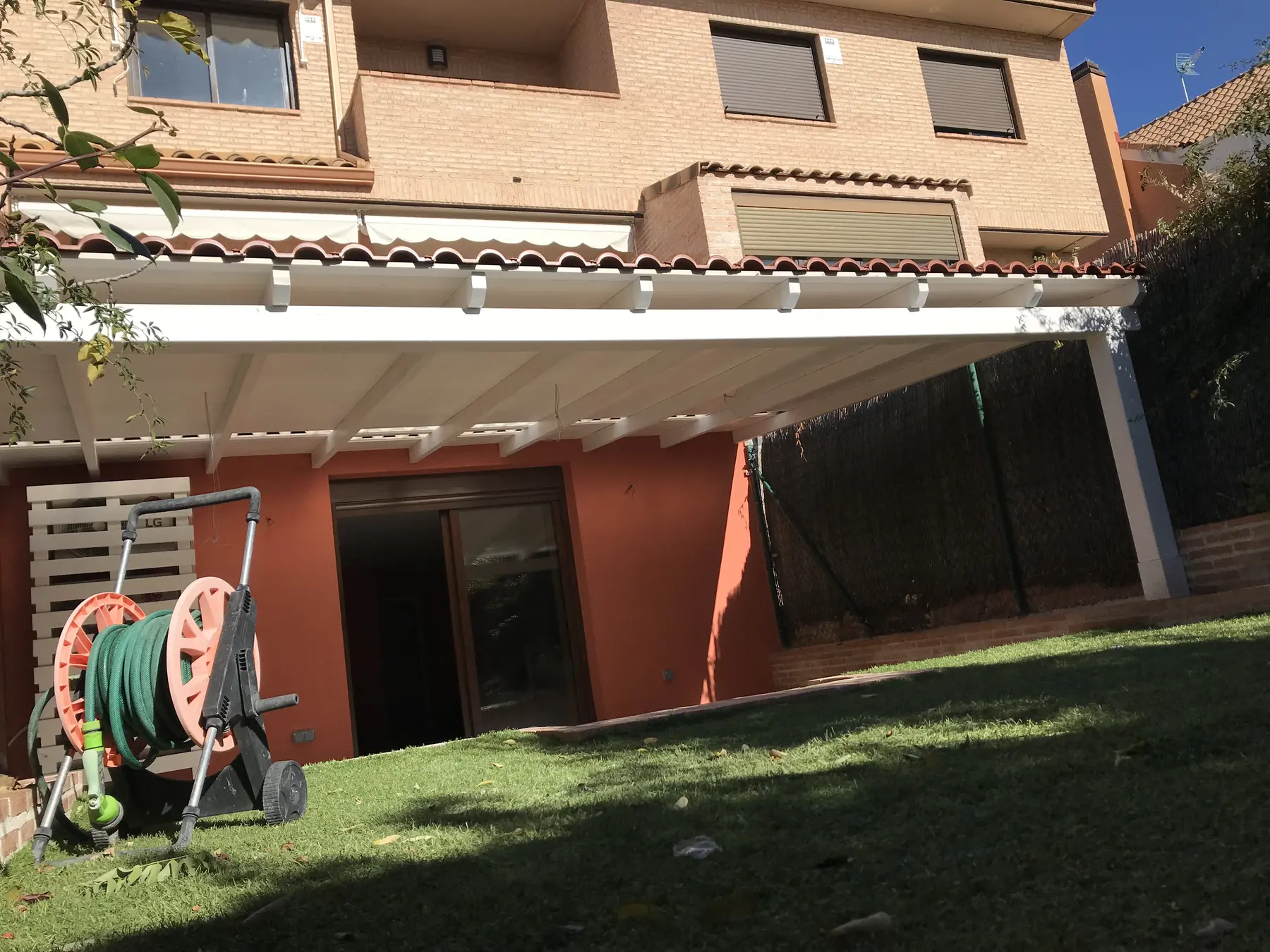 Porche de madera adosado con toldo y zona exterior de vivienda