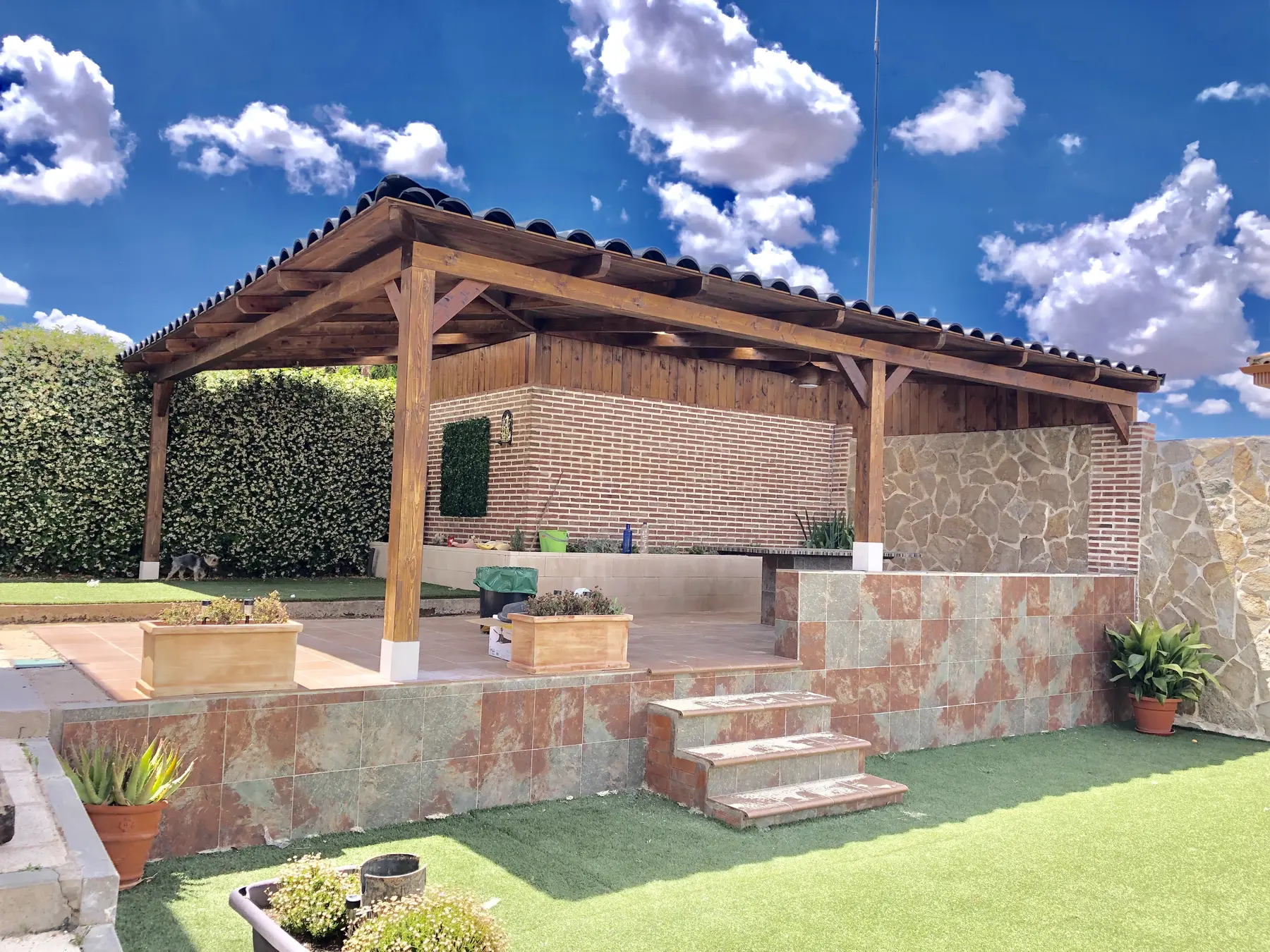 Porche de madera adosado sobre muro de piedra y escalones exteriores