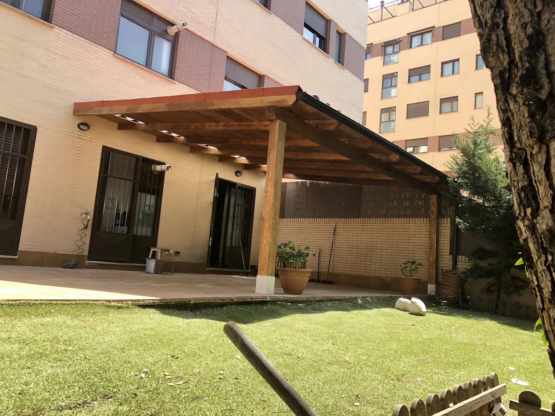 Porche adosado de madera en jardín con zona de sombra