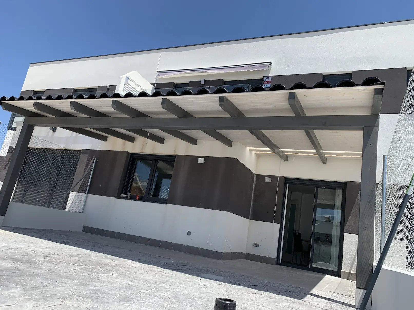 Porche adosado moderno con estructura gris junto a vivienda blanca