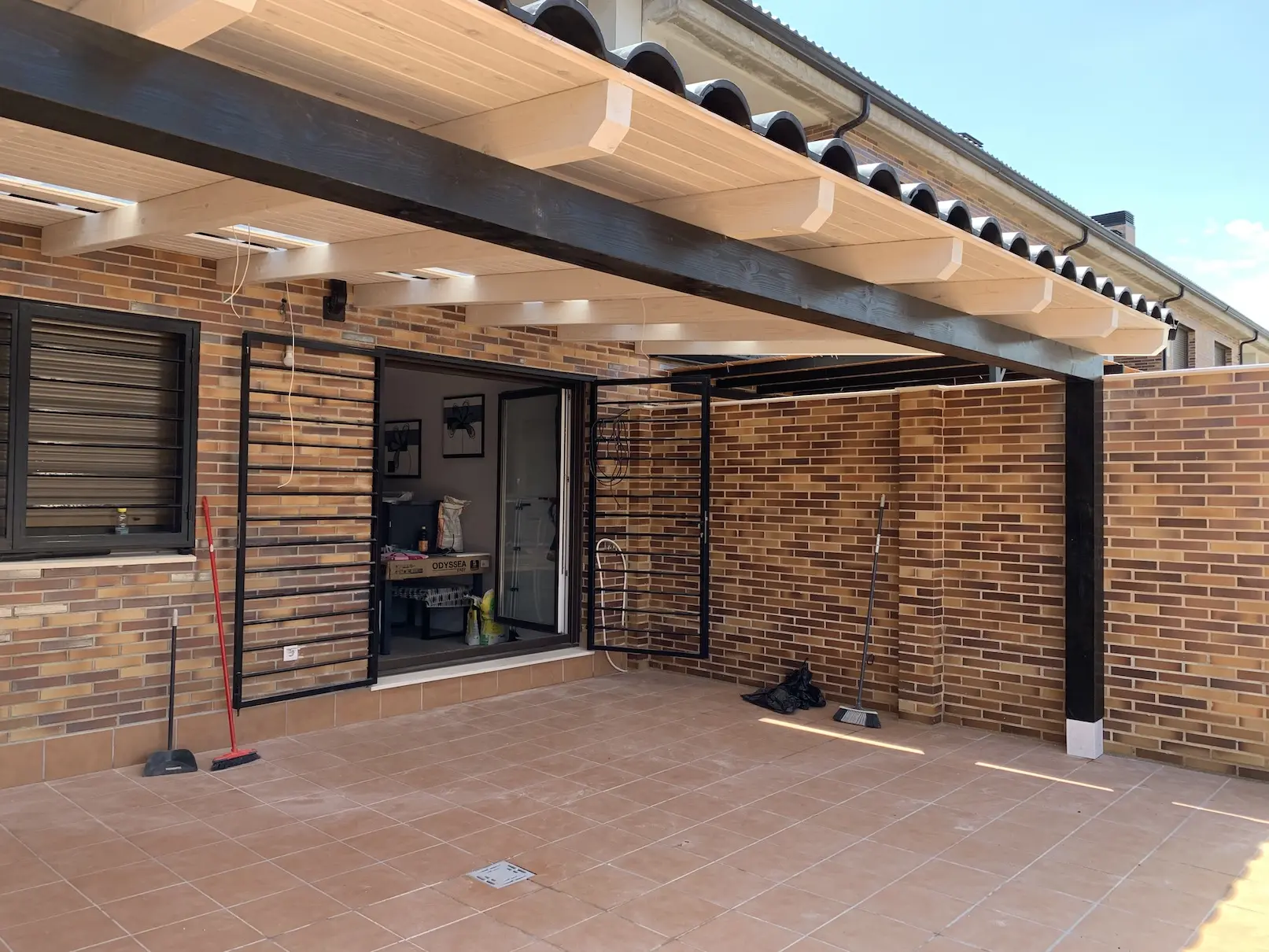 Porche de madera adosado con cubierta clara y estructura junto a vivienda