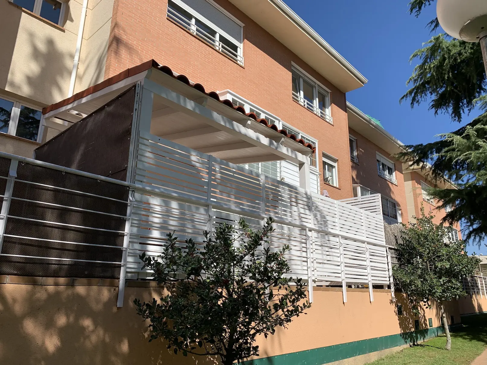 Porche de madera adosado cerrado con barandilla blanca y cubierta exterior