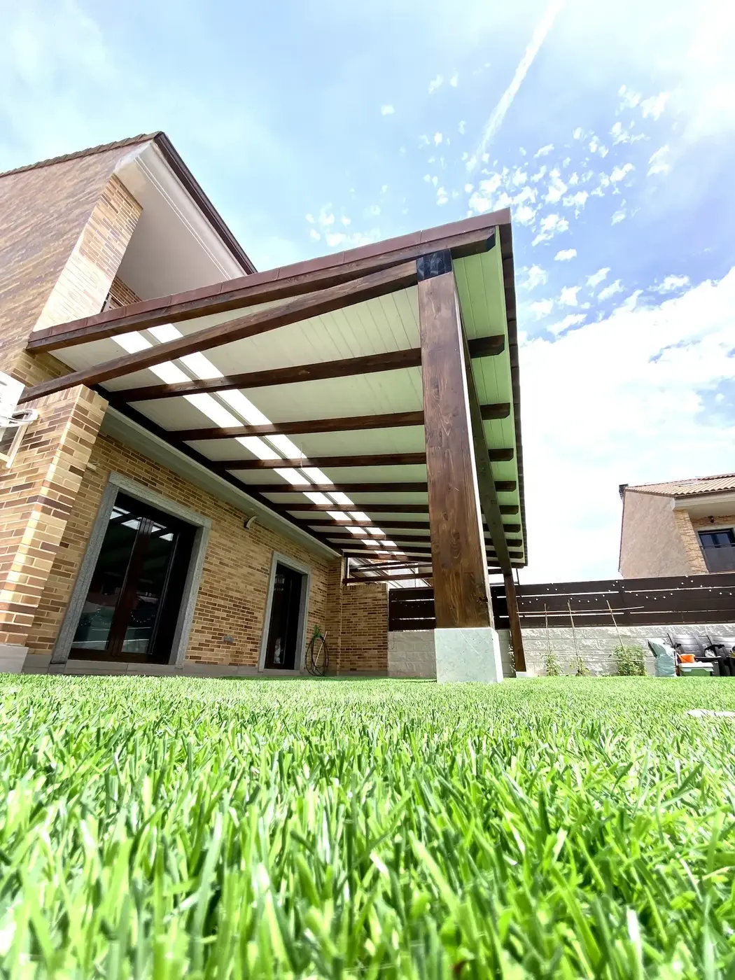 Porche de madera adosado con teja polímera instalado en vivienda